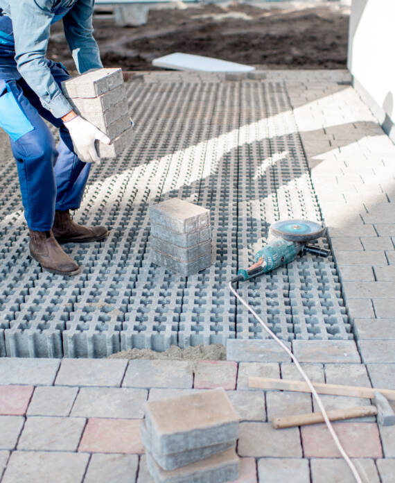 Builder carrying paving tiles on the construction site, cropped image with no face