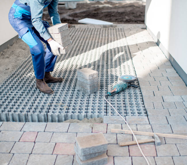 Builder carrying paving tiles on the construction site, cropped image with no face